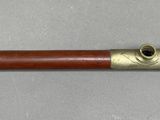 an old wooden pipe with brass fittings on a gray surface