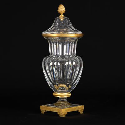 un vase ancien en verre posé sur un socle, orné de motifs dorés
