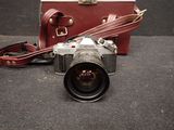 a camera sitting on the ground next to a suitcase