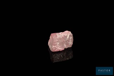 a pink diamond on a black surface with a black background