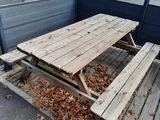 une table de pique-nique en bois sur une terrasse, avec des feuilles par terre