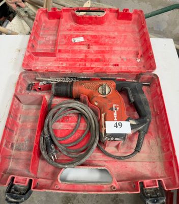 une image représentant une boîte à outils rouge contenant un cordon et une perceuse