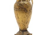 a gold vase with a bird on it sitting on a marble base