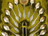des cuillères et des couteaux-cuillères en argent dans une boîte verte, avec une cuillère au milieu