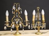 une paire de chandeliers anciens en laiton et cristal posés sur une table