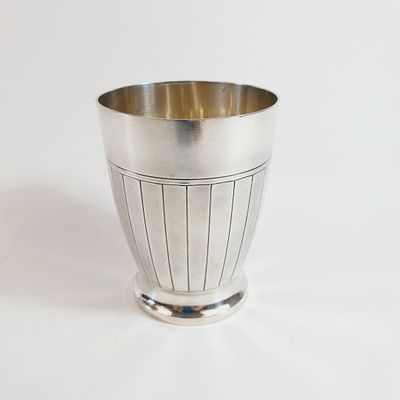 a silver cup that is sitting on a white surface