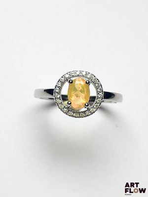 une bague ornée d'un saphir jaune ovale et de diamants, sur fond blanc