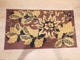 un tapis marron orné de feuilles dorées, posé sur un parquet
