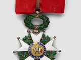 a close up of a medal on a red ribbon with a wreath