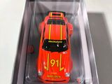 a red toy car in a clear box on a table