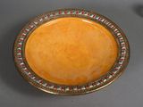 an orange plate with a gold rim sitting on top of a table