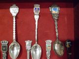 Plusieurs cuillères en argent et cuillères-cuillères sont exposées dans une vitrine.