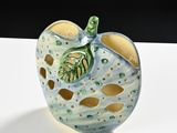 a ceramic apple with a green leaf on it