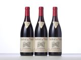 three bottles of red wine are lined up on a table