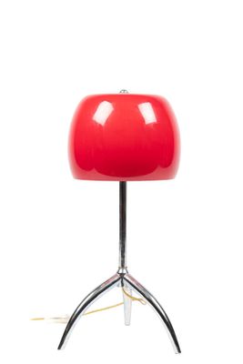 the red table lamp is sitting on a metal tripod base