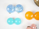 several different colored balls on a white surface next to a bowl