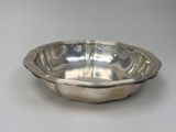 silver plated bowl on a white table with a white background