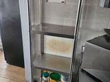 une étagère métallique dans une cuisine, sur laquelle sont posées des casseroles et des poêles