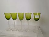 quatre verres à vin verts sont alignés sur une étagère transparente