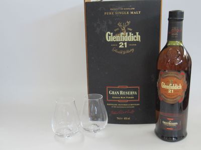 une bouteille de Glenfiddich 21 ans d'âge à côté de deux verres à vin vides