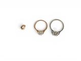 two gold rings and a silver ring on a white background