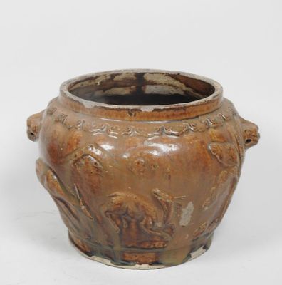 un vase brun posé sur une surface blanche