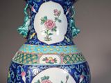 a blue vase with flowers on it sitting on a table