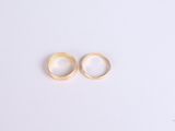 two gold wedding rings on a white surface