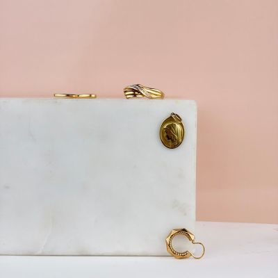white marble clutch bag with gold rings on a pink background