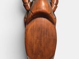an image of a wooden sculpture of a man holding his hands on his head