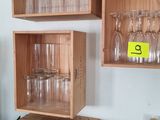 Plusieurs verres à vin vides sont empilés sur une étagère en bois
