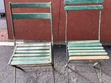 two green chairs sitting next to each other on the street