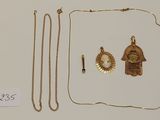 deux colliers en or et une paire de boucles d'oreilles posés sur une surface blanche