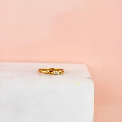 une bague en or posée sur un bloc de marbre blanc