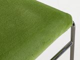 a close up of a green chair with a metal frame