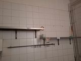 a white tiled bathroom with a metal shelf above the sink