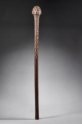 une vieille canne en bois avec un pommeau sculpté sur fond gris