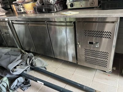 une grande cuisine en inox avec un tas de sacs par terre