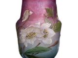 un vase avec des fleurs peintes dessus, posé sur une table