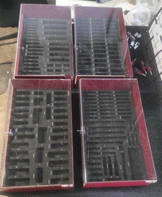 quatre boîtes contenant des objets noirs et rouges posées sur une table