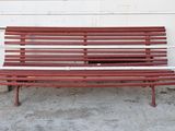 a red bench sitting on the sidewalk next to a white building