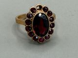 a close up of a ring with a red stone surrounded by garnetts