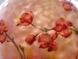 a glass vase with flowers painted on it on a table