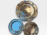 three blue and gold ashtrays on a white surface
