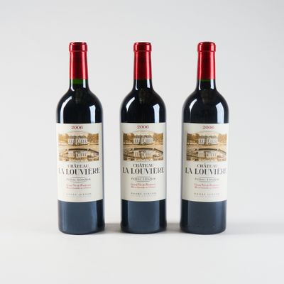 trois bouteilles de vin rouge posées l'une à côté de l'autre sur une surface blanche