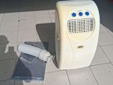 un petit climatiseur posé par terre à côté d'un rouleau de papier toilette