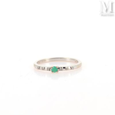 a close up of a white gold ring with a emerald and diamonds