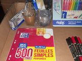 a box of pens, markers, and a notebook on a table