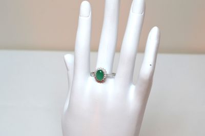 a hand with a ring on it that has a green stone on it