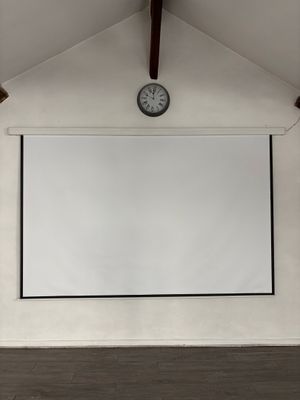 un grand écran de projection dans une pièce où se trouve une horloge accrochée au mur